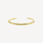 Gold cuff bracelet with small cubic zirconium stones on a white background