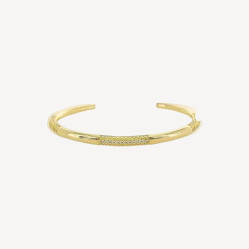 Gold cuff bracelet with small cubic zirconium stones on a white background
