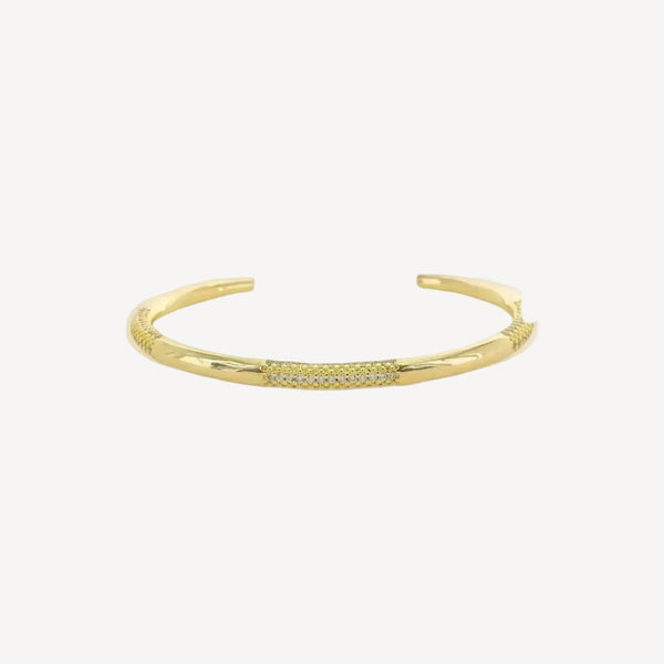 Gold cuff bracelet with small cubic zirconium stones on a white background