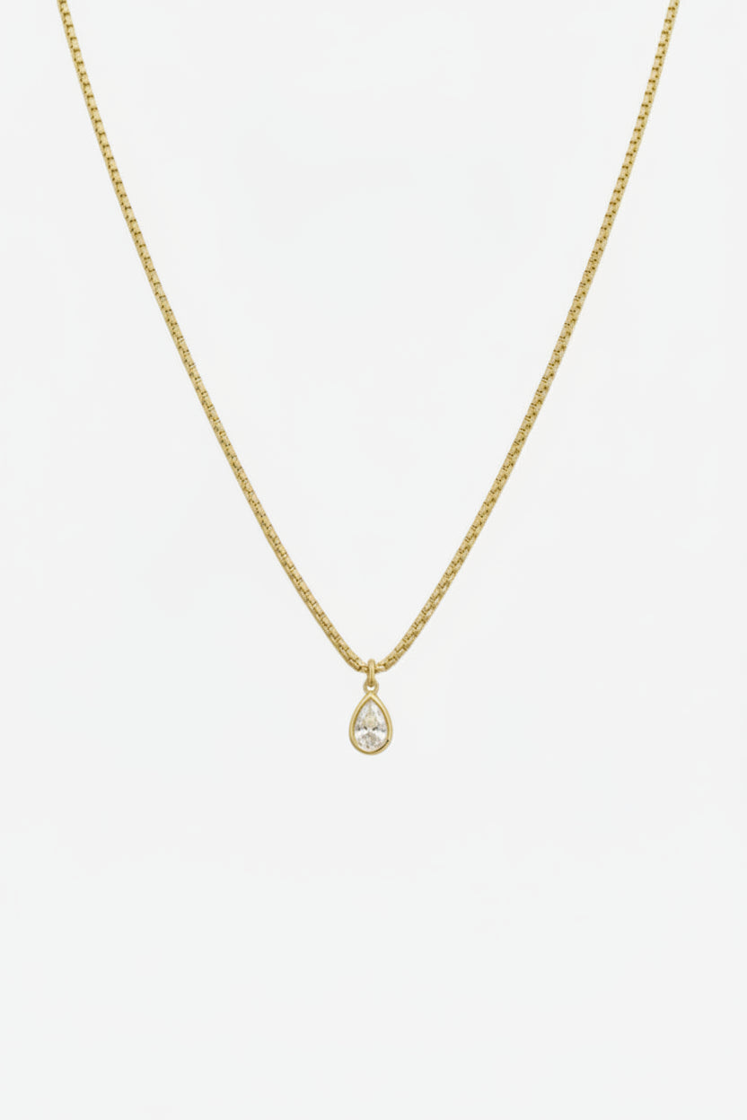 Gold necklace with a teardrop pendant on a white background