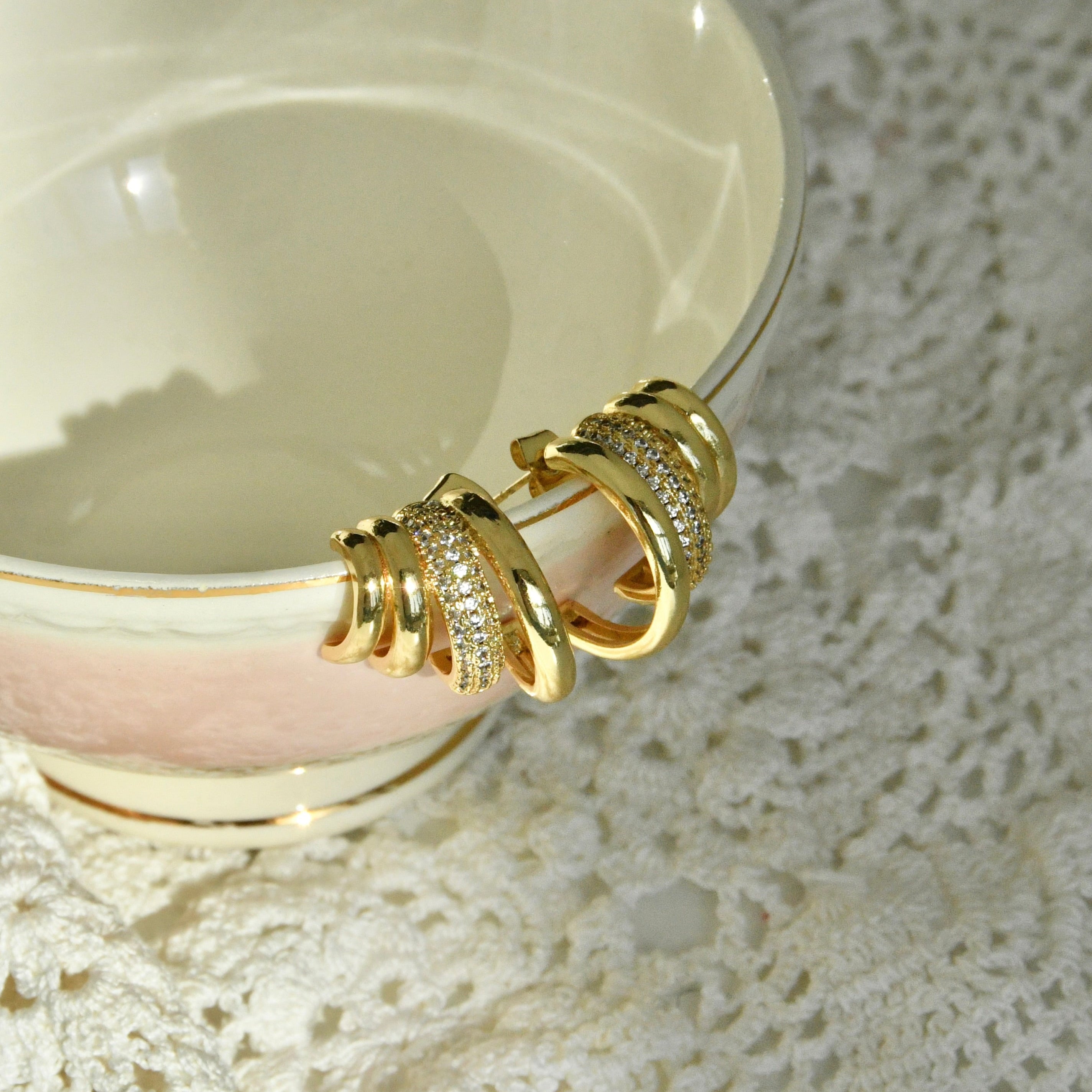 Gold bracelet on a white ceramic plate with lace background