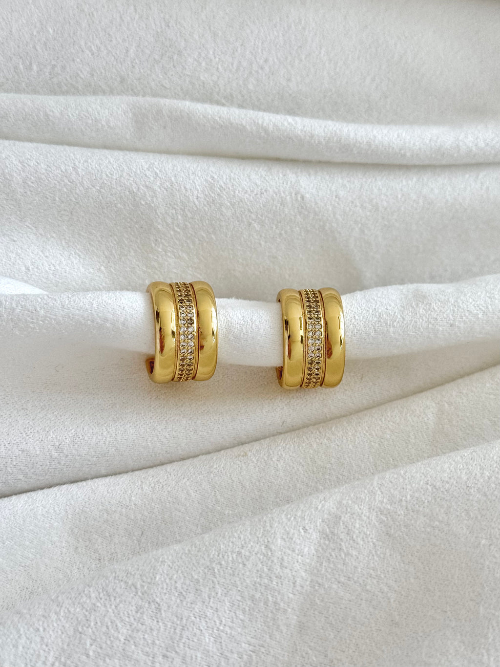 Gold hoop earrings on a white fabric background