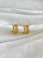 Gold hoop earrings on a white fabric background