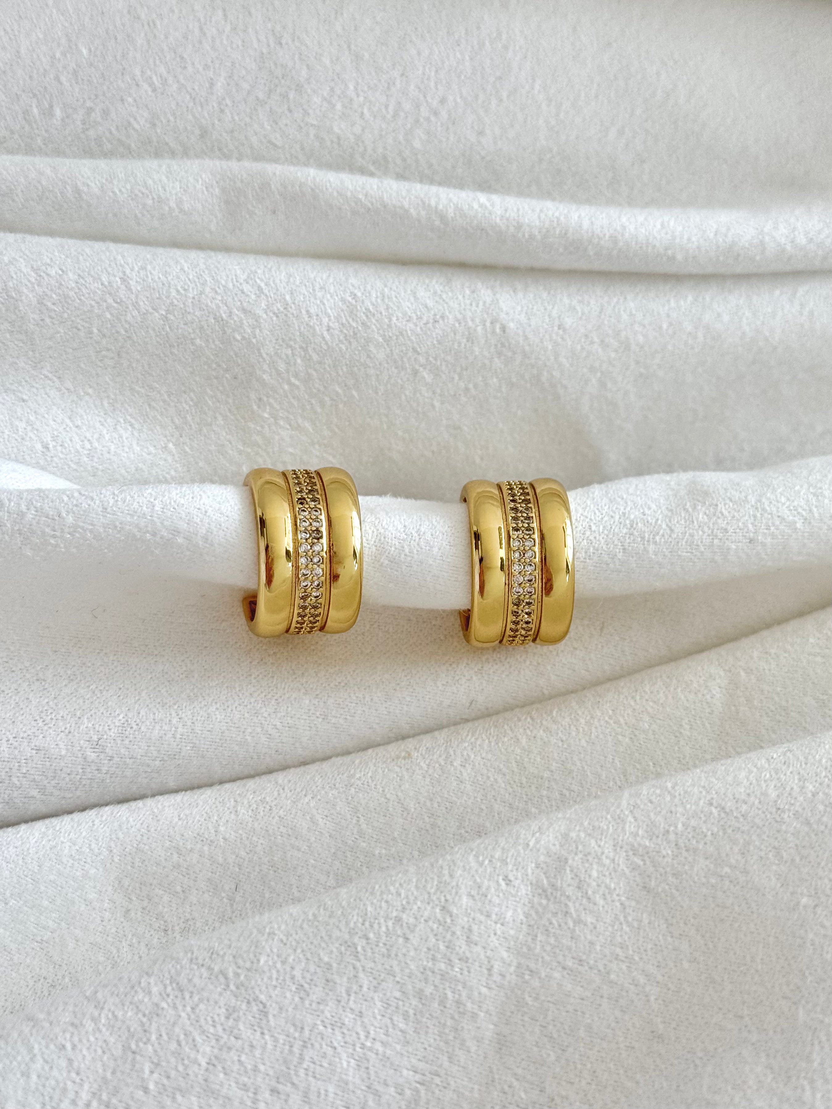 Gold hoop earrings on a white fabric background