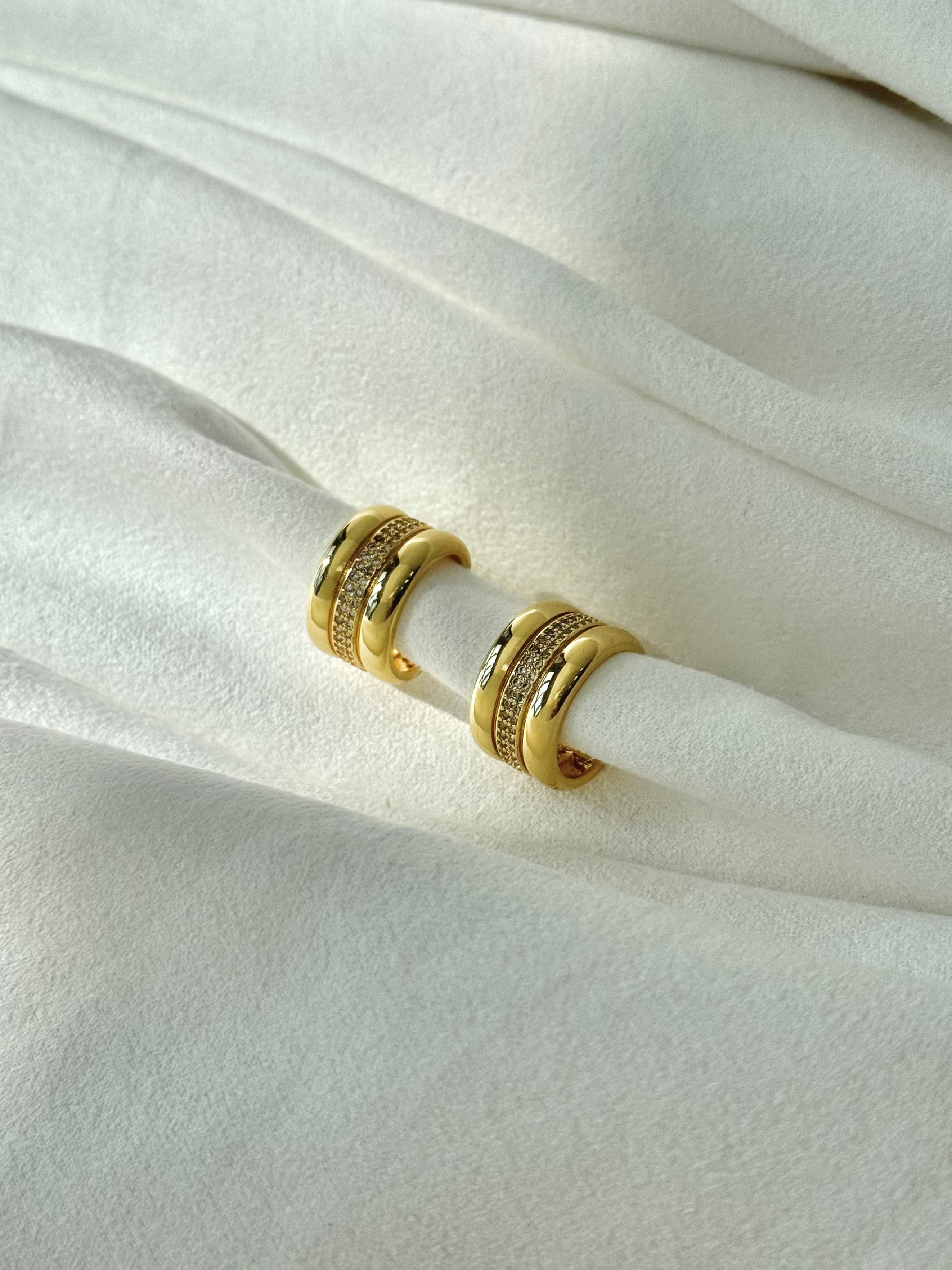 Gold hoop earrings on a white fabric background