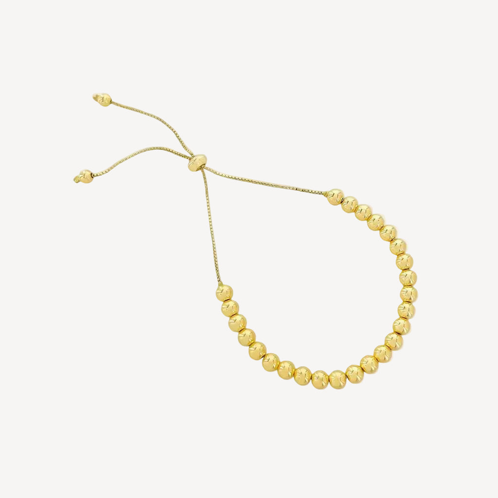 Gold beaded bracelet on a white background