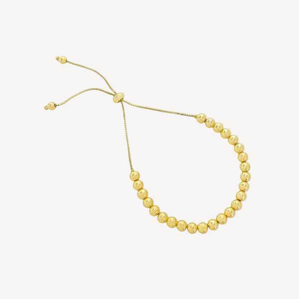 Gold beaded bracelet on a white background